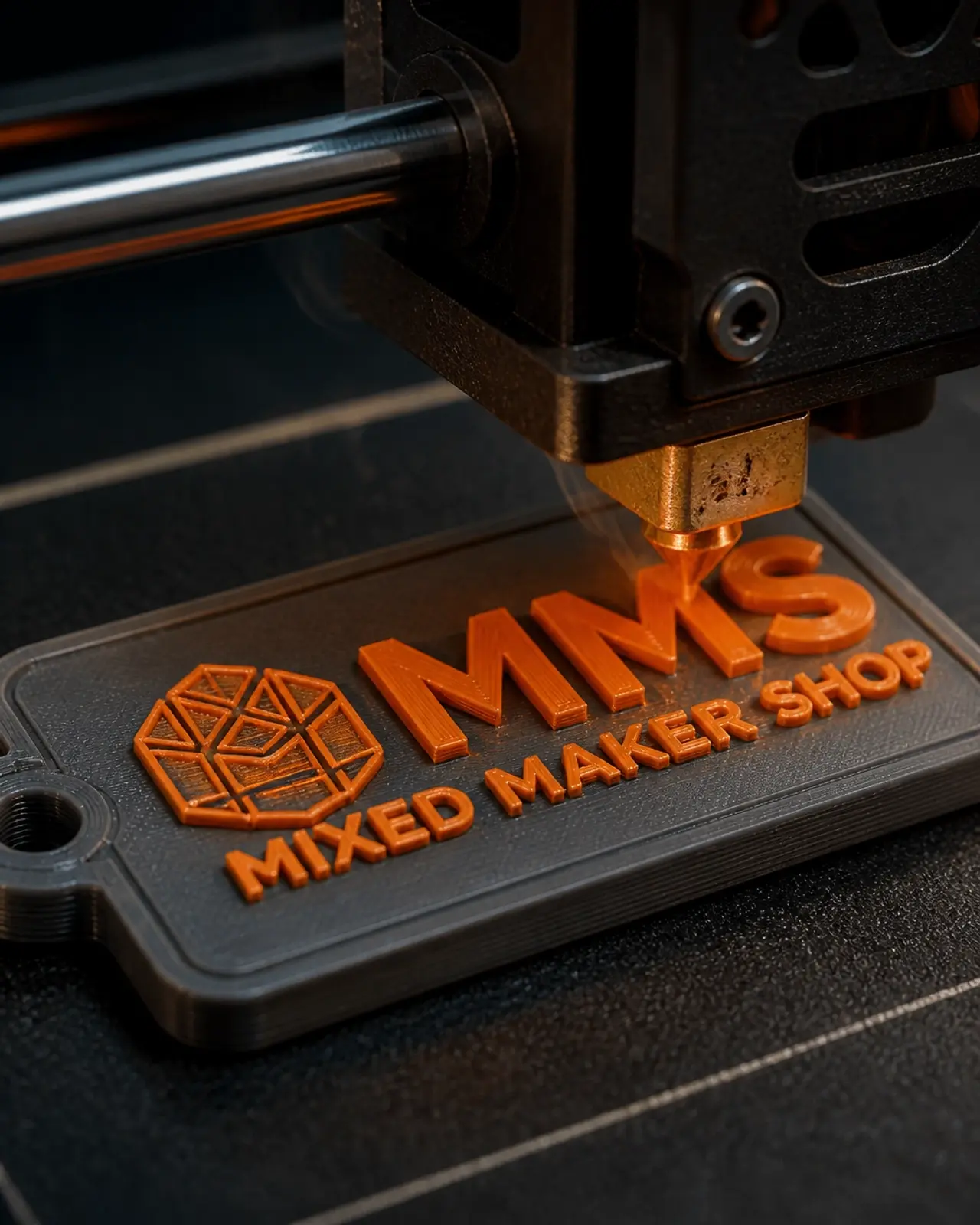 Close up of a 3D printer nozzle creating a custom orange keychain on a dark print bed