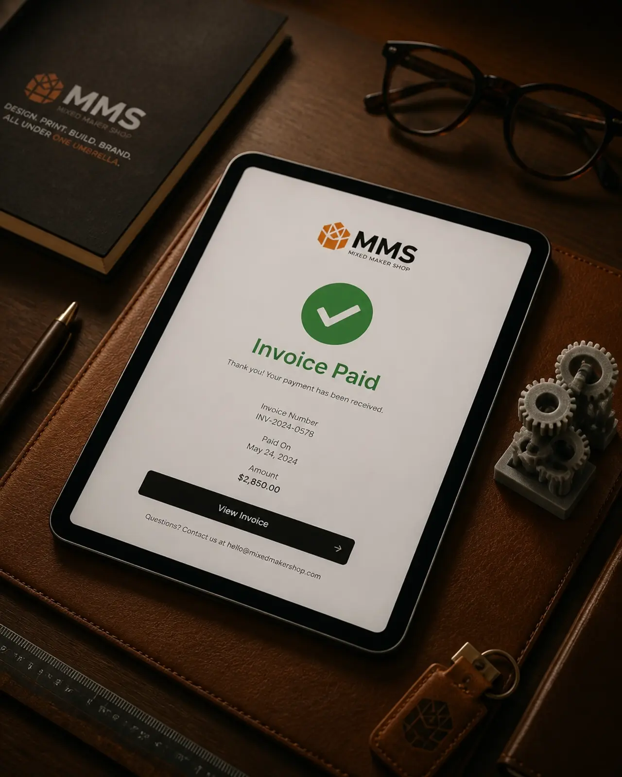 A digital tablet showing an Invoice Paid confirmation on a clean, professional desk